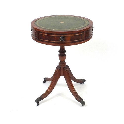 2064 - Circular yew drum table with tooled leather top, fitted with two frieze drawers and brass paw feet, ... 