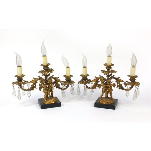 2074 - Pair of 19th century ormolu three branch candelabrum, each with two putti, cut glass drops and raise... 