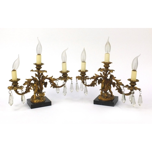 2074 - Pair of 19th century ormolu three branch candelabrum, each with two putti, cut glass drops and raise... 