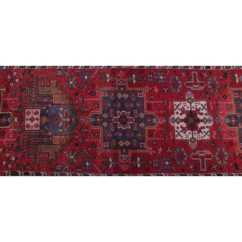 2076 - Rectangular Azarbaijan carpet runner with an all over stylised floral design onto a red ground, 320c... 