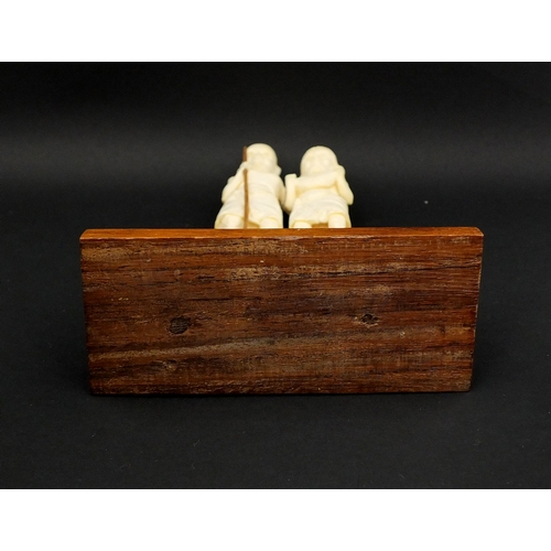 613 - Middle Eastern carved ivory group of two elders, one holding a stick, raised on a hard wood base, ov... 