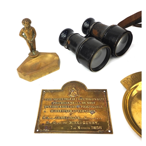 657 - Group of objects including a nude boy ashtray, 19th century brass poachers plaque, pair of binocular... 