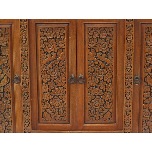2019 - Indonesian hardwood side cabinet carved with flowers and foliage fitted with four doors and a drawer... 