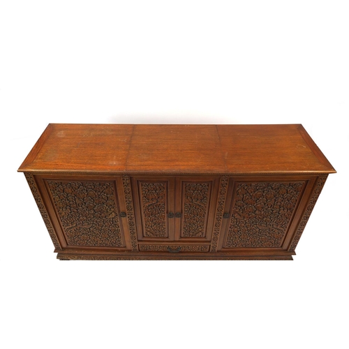 2019 - Indonesian hardwood side cabinet carved with flowers and foliage fitted with four doors and a drawer... 