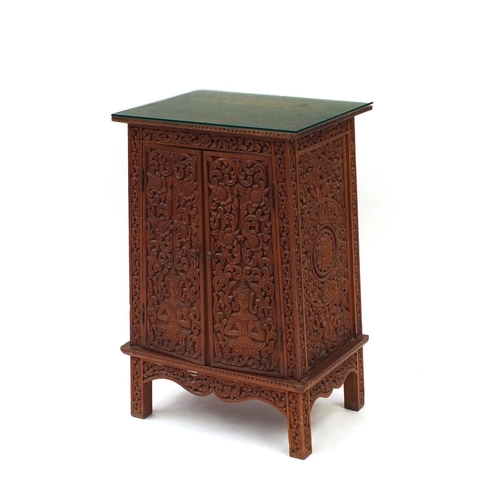 2040 - Indonesian hardwood side cabinet fitted with a pair of doors, carved with Buddha amongst flowers and... 