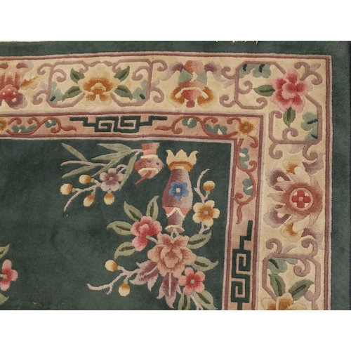 85 - Chinese super wash carpet with predominantly green ground and flowers in vases, approximately 340cm ... 