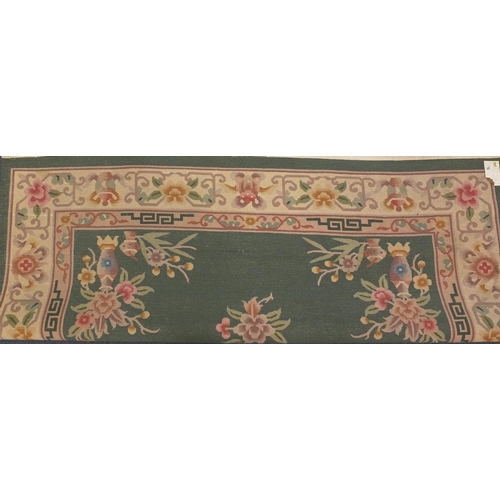 85 - Chinese super wash carpet with predominantly green ground and flowers in vases, approximately 340cm ... 