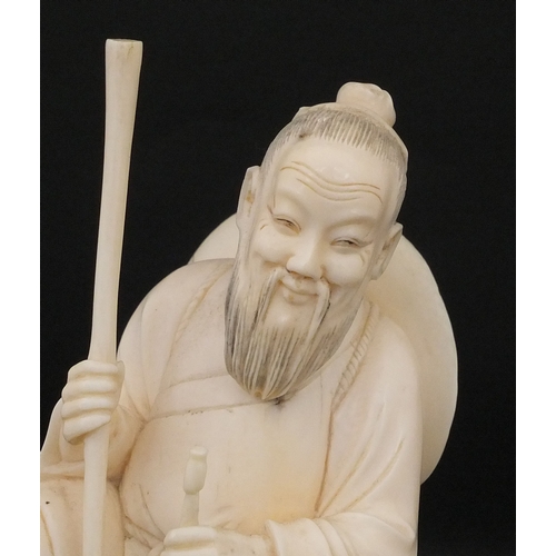 546 - Japanese carved ivory okimono, of a seated elder holding a pipe, raised on a wooden base, character ... 