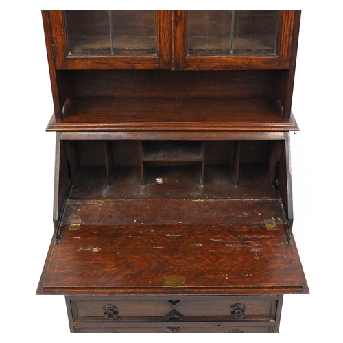 150 - Carved oak bureau bookcase fitted with a pair of leaded glass doors above a fall and four drawers, 1... 