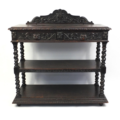 113 - Carved oak three tier buffet carved with lions heads and floral motifs, fitted with two frieze drawe... 