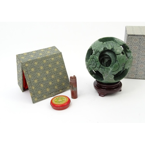 245 - Boxed Oriental carved soapstone puzzle ball raised on a hardwood stand and a soapstone seal set with... 