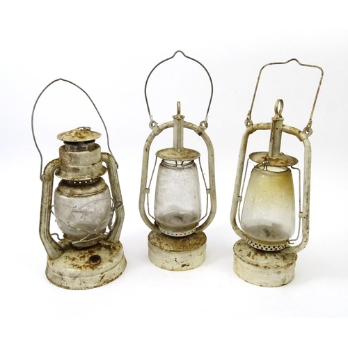 562 - Three vintage white painted metal and glass lanterns with swing handles, the largest 40cm high