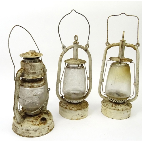 562 - Three vintage white painted metal and glass lanterns with swing handles, the largest 40cm high