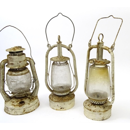 562 - Three vintage white painted metal and glass lanterns with swing handles, the largest 40cm high