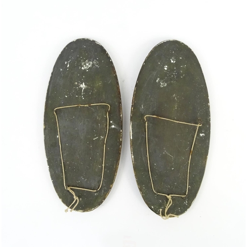 692 - Pair of oval relief plaster plaques of a lady water carrier and a lady holding a flaming torch