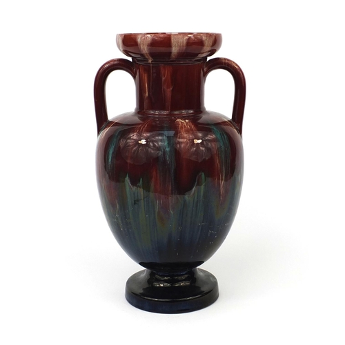 473 - Red and green glazed art pottery vase with twin handles, in the style of Christopher Dresser, 35cm h... 