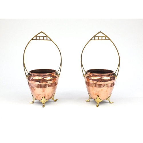 786 - Pair of Art Nouveau four footed brass and copper baskets, with planished decoration, each 34cm high