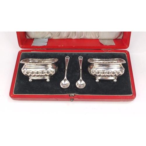 864 - Pair of silver salts with embossed decoration and ball feet with matched spoons, housed in a fitted ... 