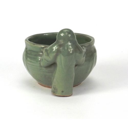 521 - Oriental celadon glazed pot with a figure beside, 12cm high x 16cm wide