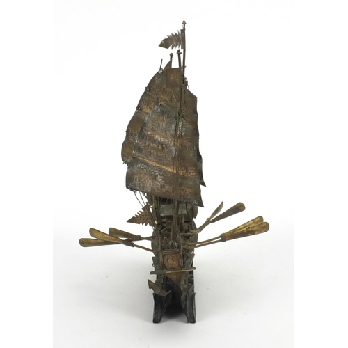 576 - Chinese silver coloured metal model of a junk raised on  wooden base, character marks to the reverse... 