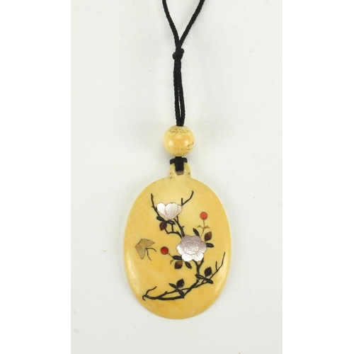 550 - Japanese Shibayama ivory pendant on string necklace, inlaid with butterfly amongst flowers, the pend... 