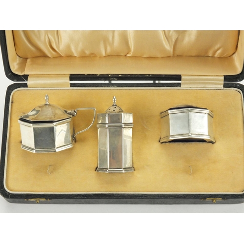 821 - Art Deco octagonal silver three piece cruet with blue glass liners, housed in a fitted case, W.M.CO ... 