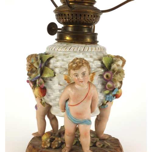 664 - Continental hand painted porcelain oil lamp base with putti supports, overall 40cm high