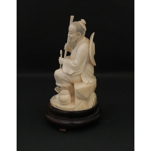 546 - Japanese carved ivory okimono, of a seated elder holding a pipe, raised on a wooden base, character ... 