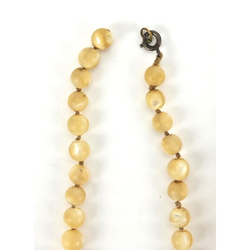 551 - Two Chinese ivory graduated bead necklaces, together with a Mother of Pearl example, the largest bea... 