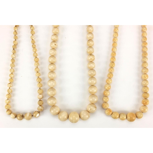 551 - Two Chinese ivory graduated bead necklaces, together with a Mother of Pearl example, the largest bea... 