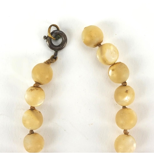 551 - Two Chinese ivory graduated bead necklaces, together with a Mother of Pearl example, the largest bea... 