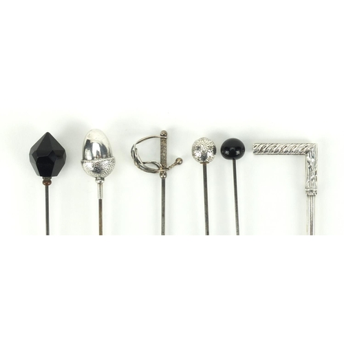 12 - Six vintage hat pins including a silver acorn example, one in the shape of a sword and a walking sti... 