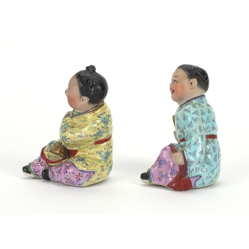 485 - Pair of Chinese seated figures of children, both hand painted in the famille rose palette, the large... 