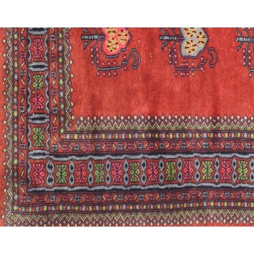 2075 - Rectangular Persian Bokhara rug having all over floral motifs onto a red ground, 173cm x 93cm