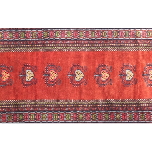 2075 - Rectangular Persian Bokhara rug having all over floral motifs onto a red ground, 173cm x 93cm