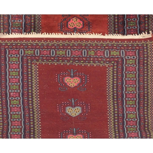 2075 - Rectangular Persian Bokhara rug having all over floral motifs onto a red ground, 173cm x 93cm