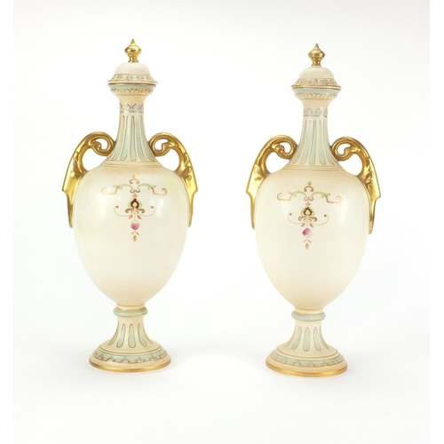 2214 - Pair of Crown Devon blush ivory urns and covers with gilt handles, each decorated with urns and flow... 