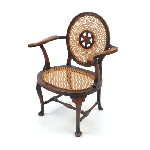 74 - Stained beech elbow chair, the circular cane back with star motif and cane and seat, the back with s... 