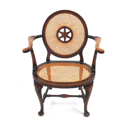 74 - Stained beech elbow chair, the circular cane back with star motif and cane and seat, the back with s... 