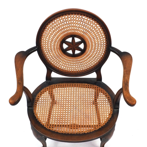 74 - Stained beech elbow chair, the circular cane back with star motif and cane and seat, the back with s... 