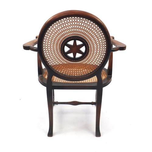 74 - Stained beech elbow chair, the circular cane back with star motif and cane and seat, the back with s... 