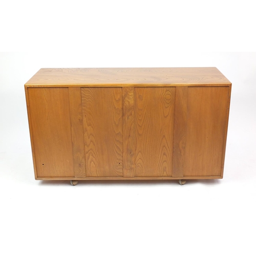 2018 - Ercol light elm sideboard fitted with three cupboard doors above two drawers, label to the interior,... 