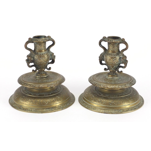 24 - Pair of antique Venetian bronze candlesticks with grotesque twin handles and foliate engraving, each... 