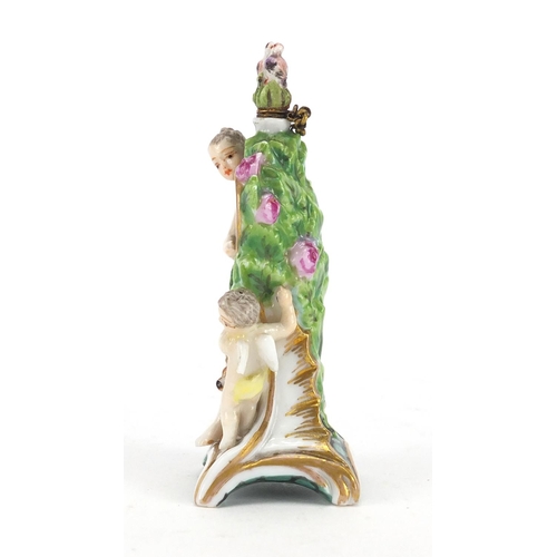 446 - Chelsea girl in the swing style porcelain scent bottle, modelled with a lady, dog, cherub and clock,... 
