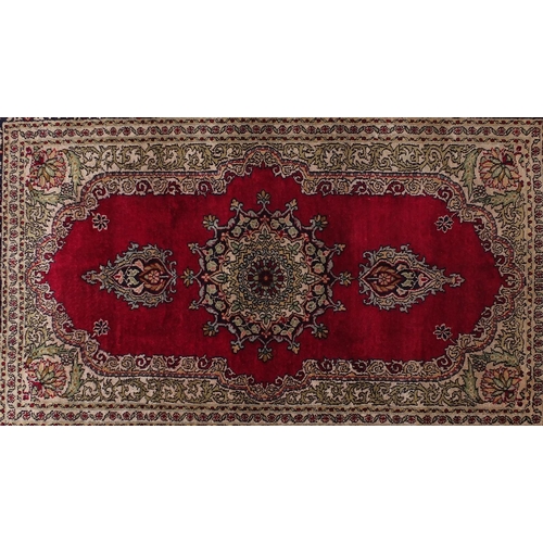 2031 - Rectangular Persian silk rug having all over floral motifs onto a red ground, 98cm x 63cm