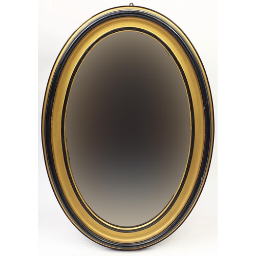23 - Oval ebonised and gilt painted wall hanging mirror, 110cm x 80cm