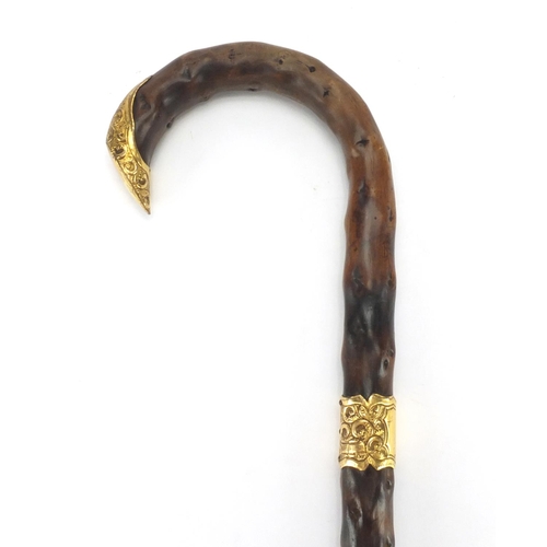 155 - Naturalistic wooden walking cane with gold coloured metal mounts, 86cm in length