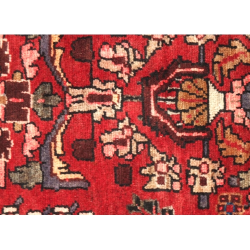 2050 - Persian Shiraz rectangular carpet runner, having all over floral motifs onto a dark red ground, 277c... 