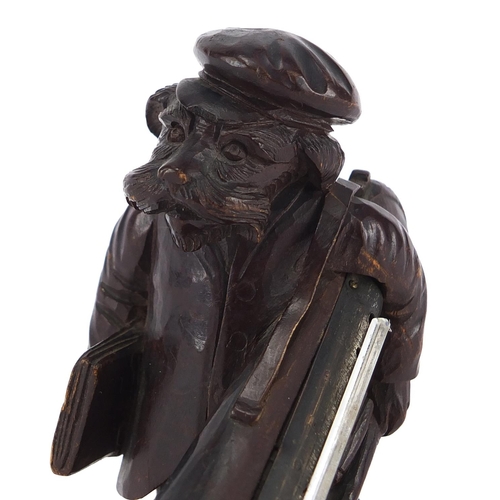 46 - Black forest desk thermometer carved in the form of a dog holding a trombone, 13cm high