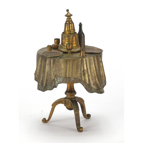 91 - Novelty brass bell push in the form of a dining table, 14cm high